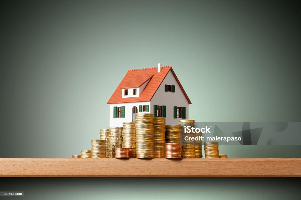 miniature model house standing on a stack of coins.
